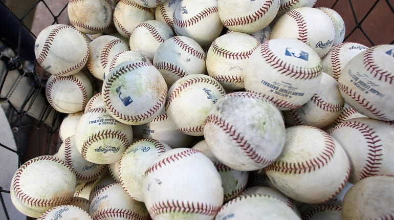 Baseballs are seen in a bucket during batting practice between...
