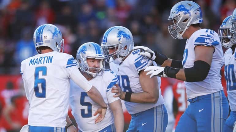 Matt Prater of the Lions celebrates with teammates after kicking...