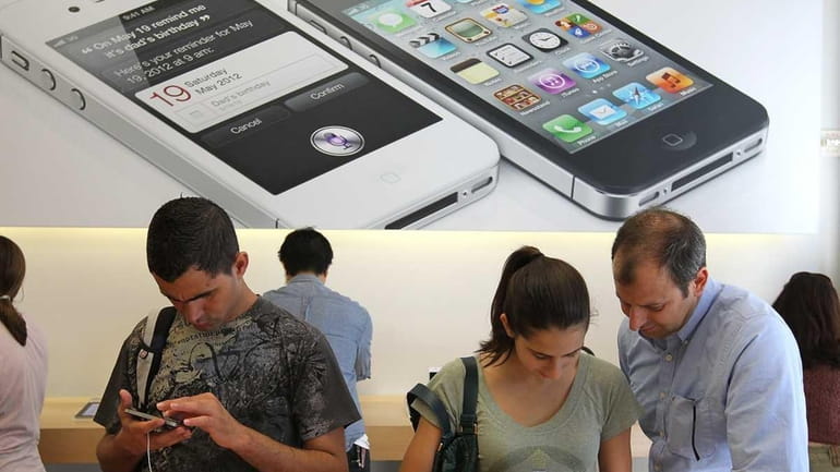 In this file photo, Apple Store customers look at the...