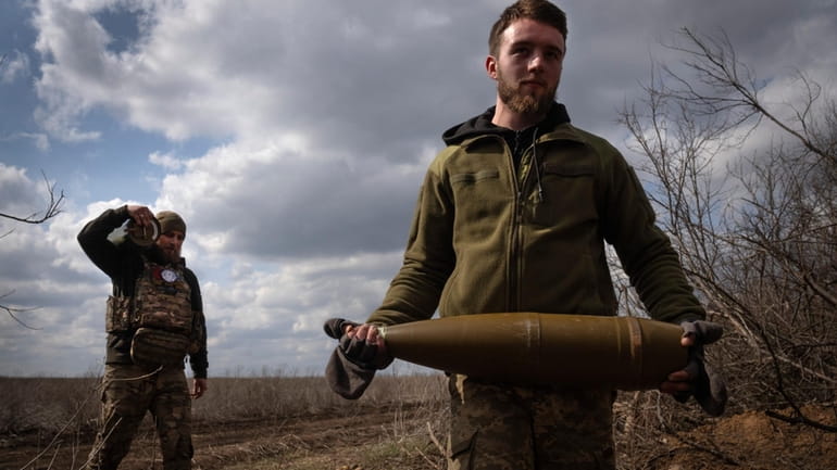 Ukrainian soldiers carry shells to fire at Russian positions on...