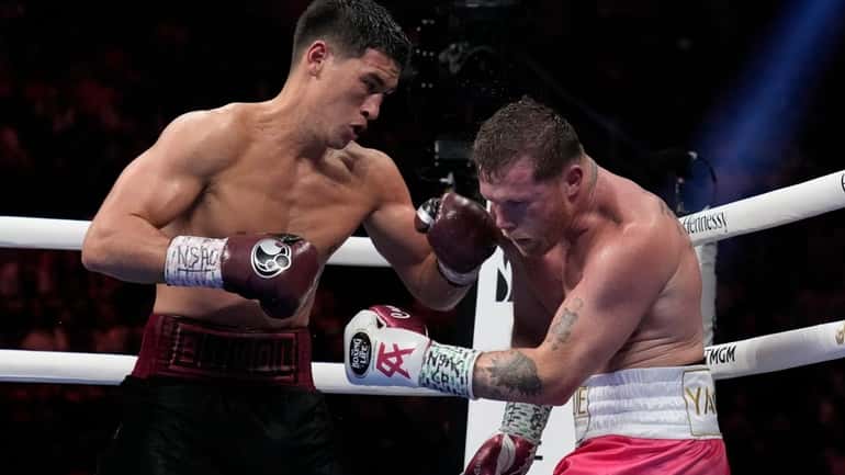 Dmitry Bivol, left, of Kyrgyzstan, throws a punch against Canelo...