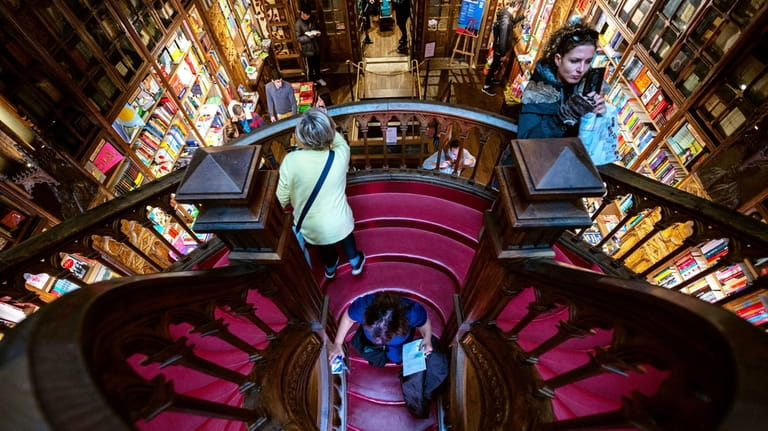 Tourists take pictures inside the Livraria Lello bookshop, a Gothic...