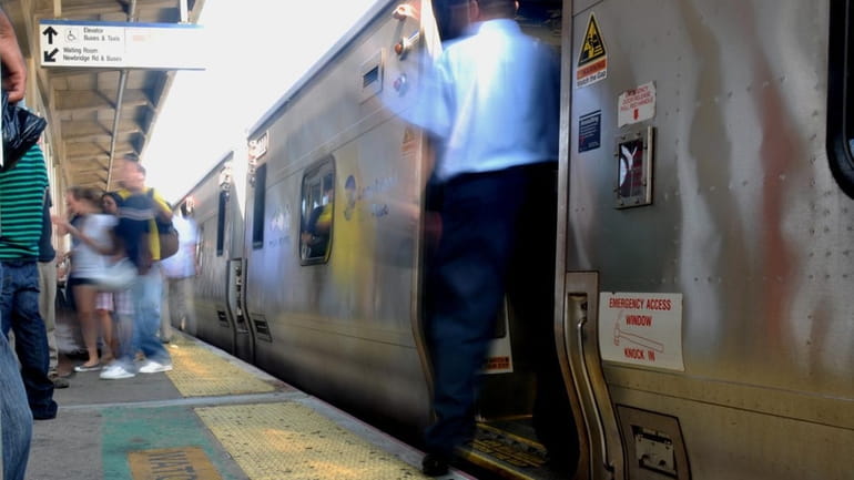 A Long Island Rail Road conductor holds the doors as...