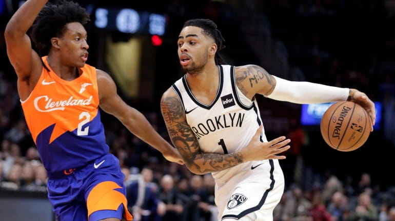 The Nets' D'Angelo Russell drives against the Cavaliers' Collin Sexton...