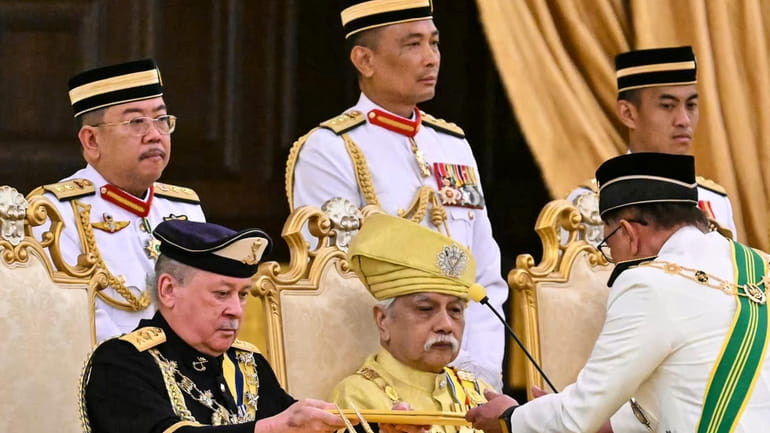 Sultan of Johor, Sultan Ibrahim Iskandar, left, receives documents from...