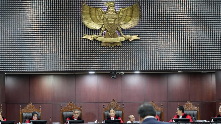 Chief Judge Suhartoyo, center, listens as Coordinating Minister for Economics...