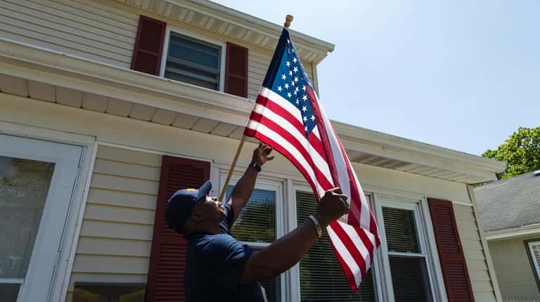 Chris Martin, a case manager, adjusts an American flag at...