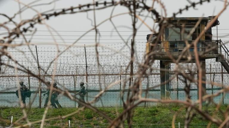 South Korean army soldiers pass by the barbed-wire fence in...