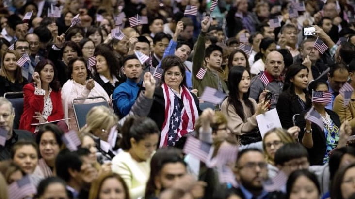 People wave U.S. flags during a naturalization ceremony at the...