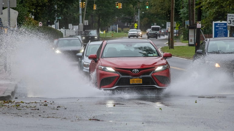 Cars splash through puddles on Park Avenue and East Main...
