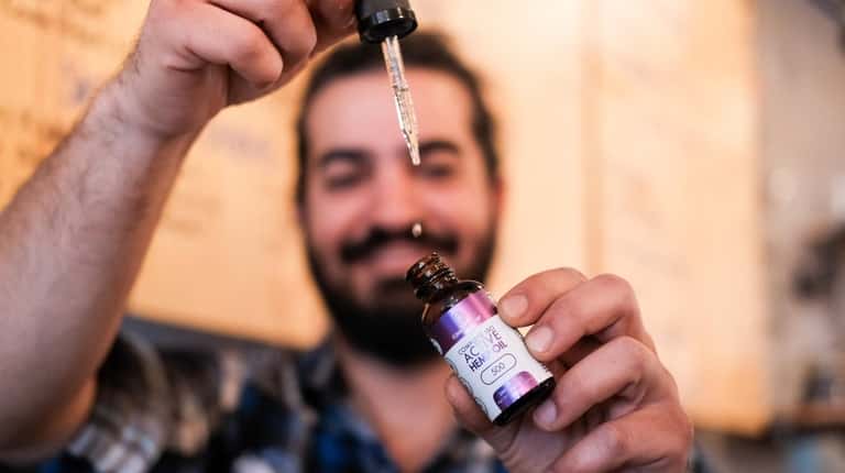 Arsalan Pourmand, owner of Flux Coffee, holds CBD oil, which...