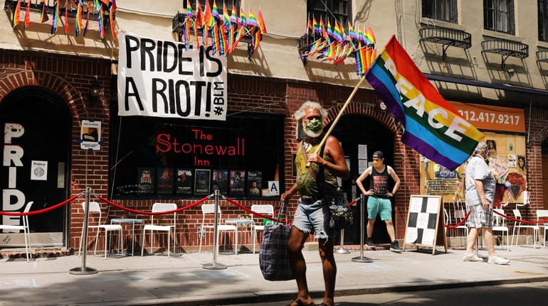 People walk by the Stonewall Inn, an iconic bar for...