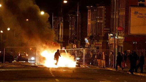 A rioter walks through a burning barricade in the Toxteth...