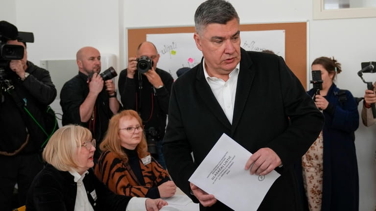 Croatia's President Zoran Milanovic holds his ballot at a polling...