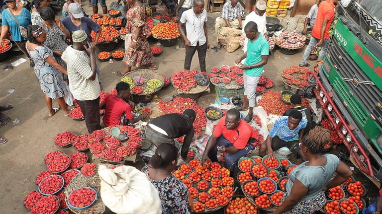 Pedestrians shop for tomatoes and other food items at the...