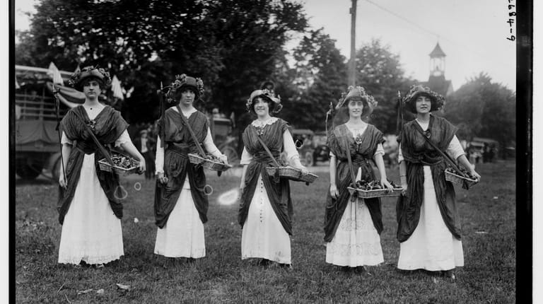 Women in suffrage pageant and parade sell flowers on Long...