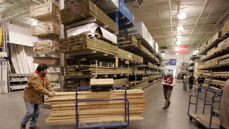 A shopper pushes a cart of lumber through a Lowes...