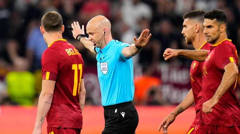 Referee Anthony Taylor signals no penalty for Sevilla after checking...
