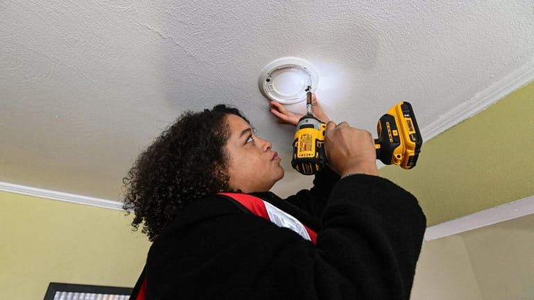 Assemb. Michaelle Solages (D-Elmont) installs a smoke detector in a home on Dutch...