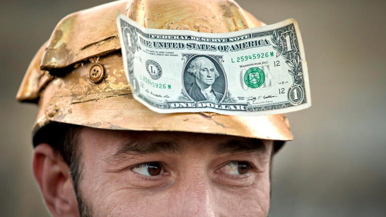 A man wears a one dollar bill on a miner's...