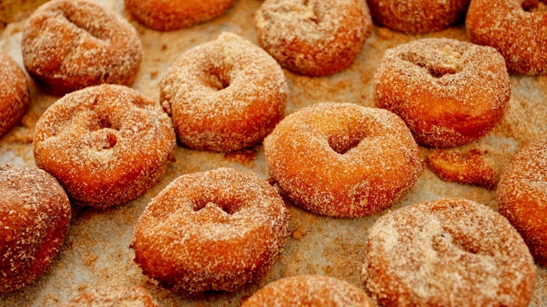 Homemade apple cider donuts are dusted with cinnamon sugar at...