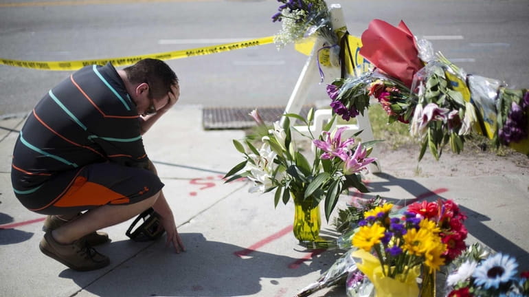 Noah Nicolaisen, of Charleston, S.C., kneels at a makeshift memorial...