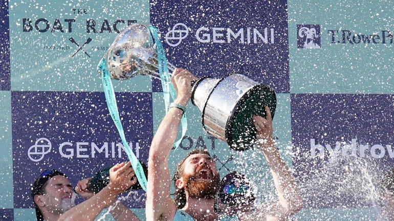 The Cambridge men's team celebrates with the trophy following the...