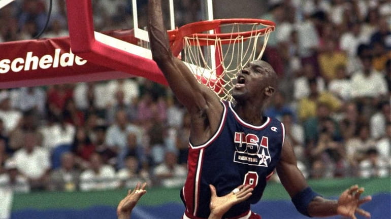USA's Michael Jordan sails high above teammate Magic Johnson knocking...