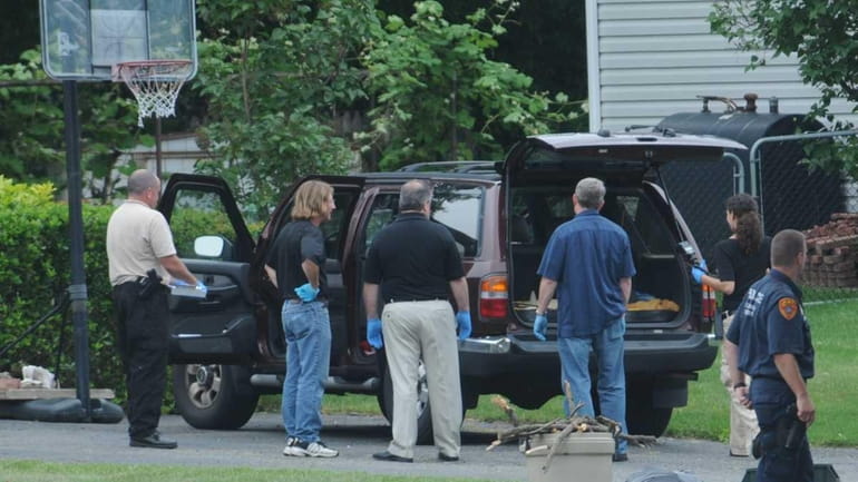 Investigators inspect a vehicle in driveway of home at 30...