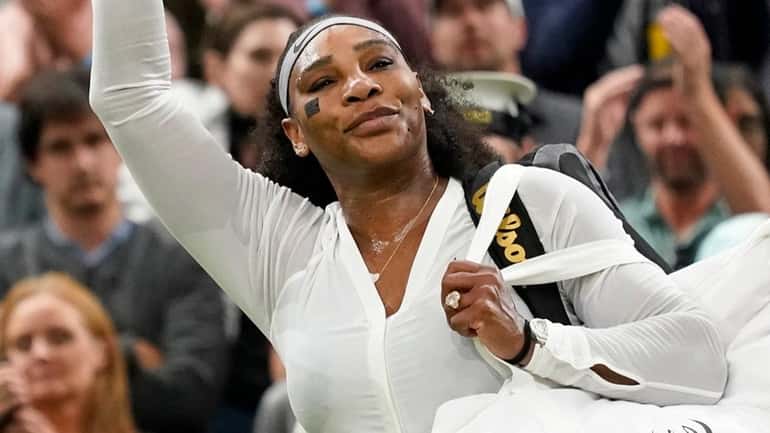 Serena Williams waves as she leaves the court after losing...