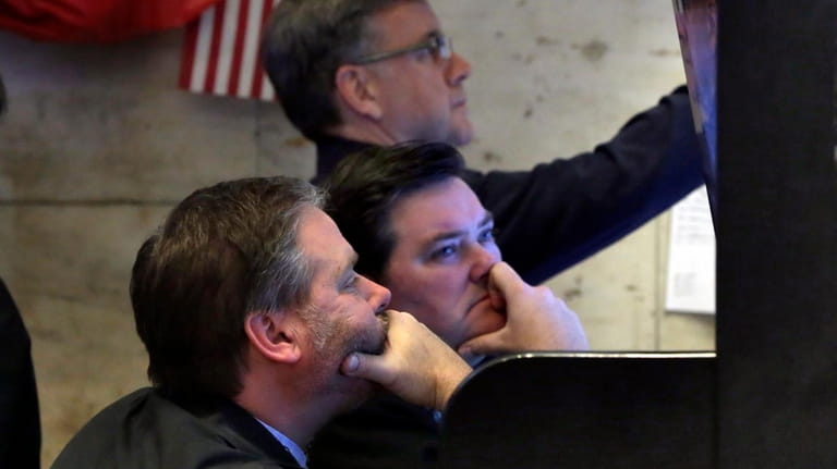 A trio of traders watch their screens in a booth...