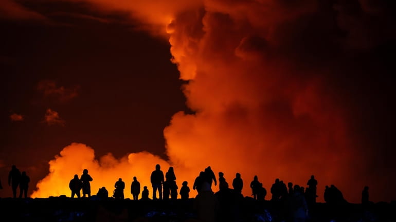 Spectators watch plumes of smoke from volcanic activity between Hagafell...