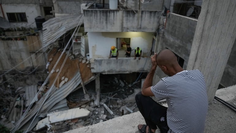 Palestinians inspect a damaged building following an Israeli army raid...