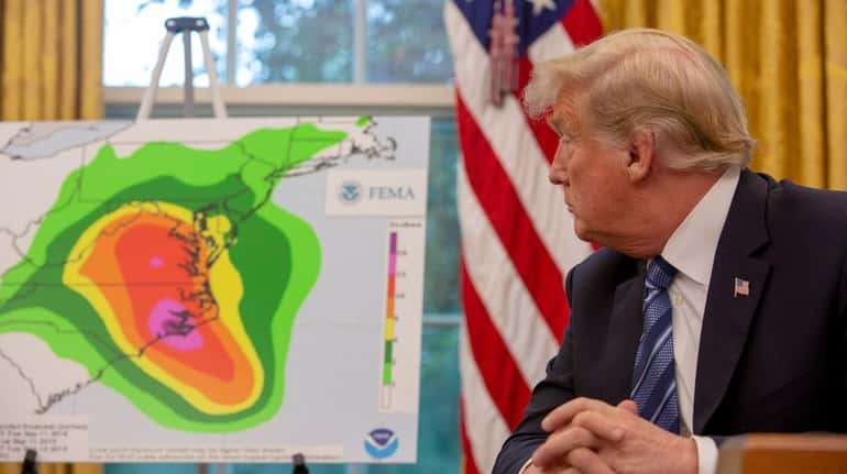 President Donald Trump looks at a map showing the potential...