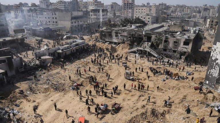 Palestinians walk through the destruction left by the Israeli air...