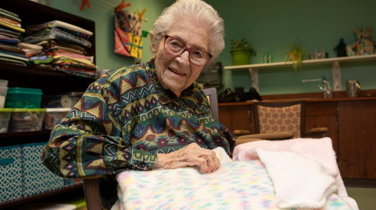 Atria resident Selma Spector, 98, works on a knitted baby blanket...
