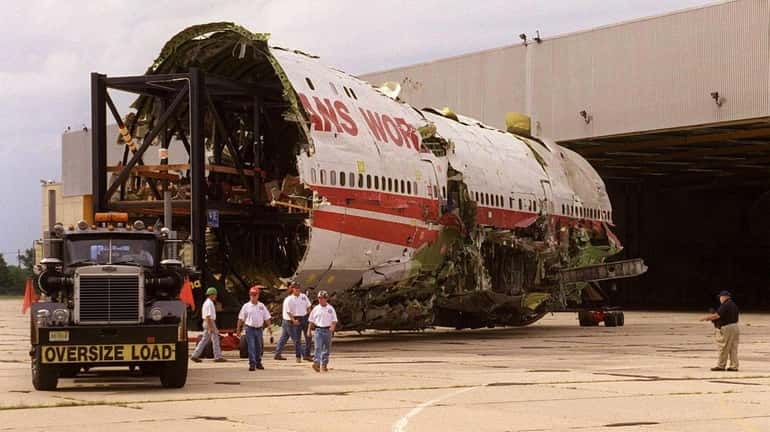 A tractor moves the reconstructed wreckage of TWA Flight 800...