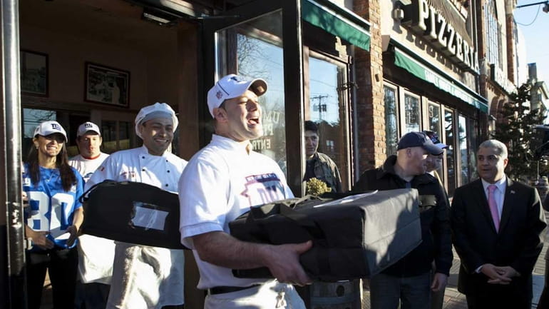 Vincenzo Corteo carries pizza pies to a sheriff's car that...