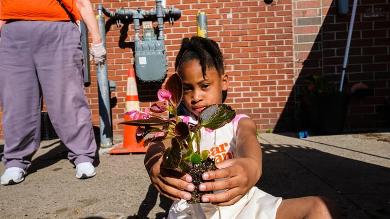 Emery Demby-Cummings, 7, shows flowers she's planting during the Spin...
