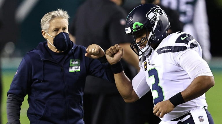 Pete Carroll fist-bumps Russell Wilson of the Seahawks during warmups against...