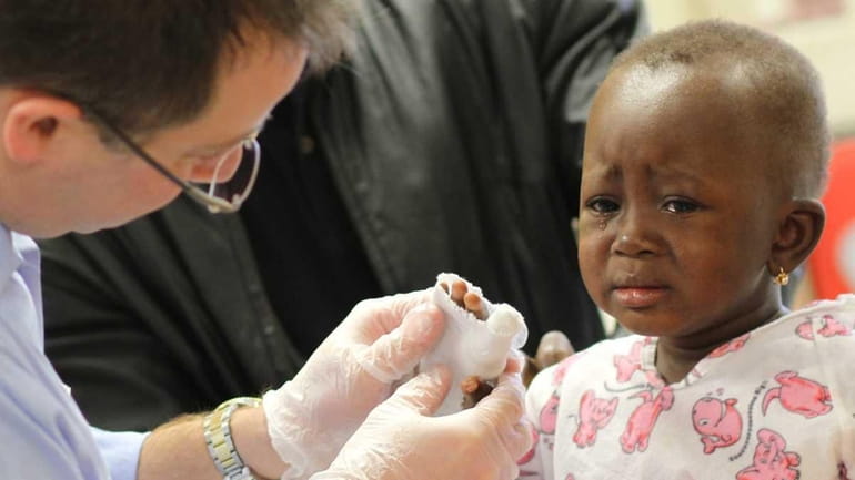 Guedalia Sawadogo, 2, from West Africa, is treated by therapist...