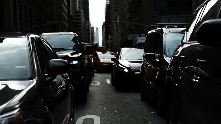 Cars pause in traffic on a busy Manhattan street on...