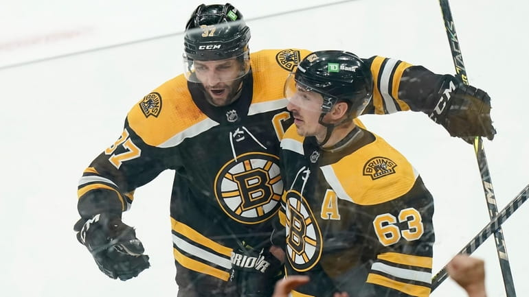 The Bruins' Patrice Bergeron, top left, celebrates with Brad Marchand, right,...