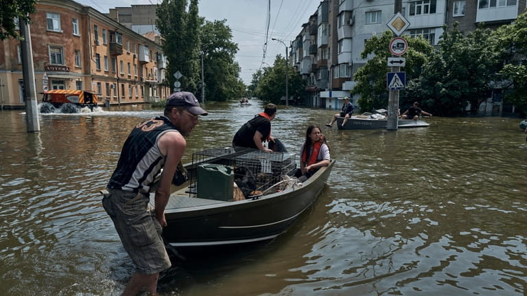 People with pets are evacuated on a boat from a...