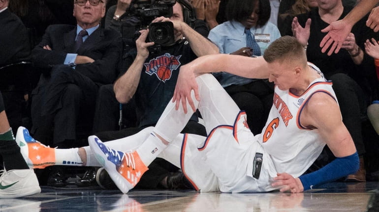 Knicks forward Kristaps Porzingis clutches his left knee after a...