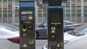 An existing pay-and-display meter, left, next to a pay-by-plate meter that...