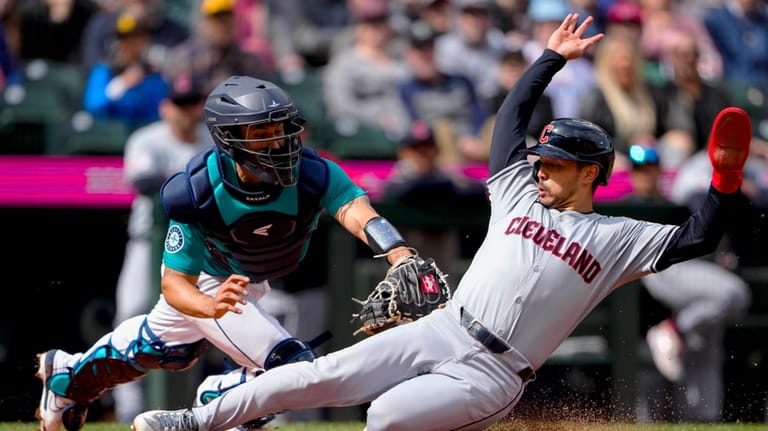 Cleveland Guardians' Steven Kwan avoids the tag from Seattle Mariners...