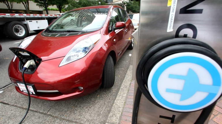 A Nissan Leaf charges at a electric vehicle charging station...