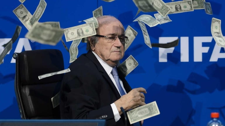FIFA president Sepp Blatter looks on with fake dollar notes...