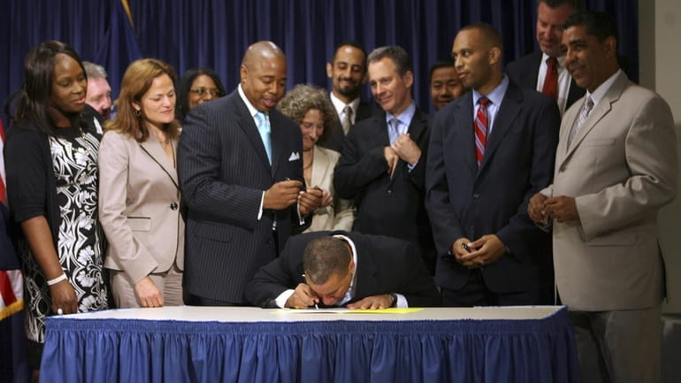 Gov. David Paterson, center, signs a bill prohibiting the New...